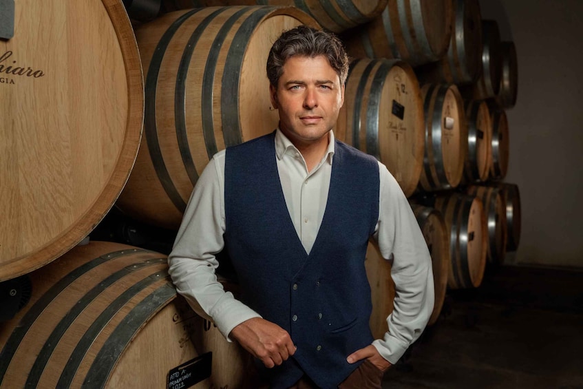 A man standing in a cellar with wooden wine barrels. 1