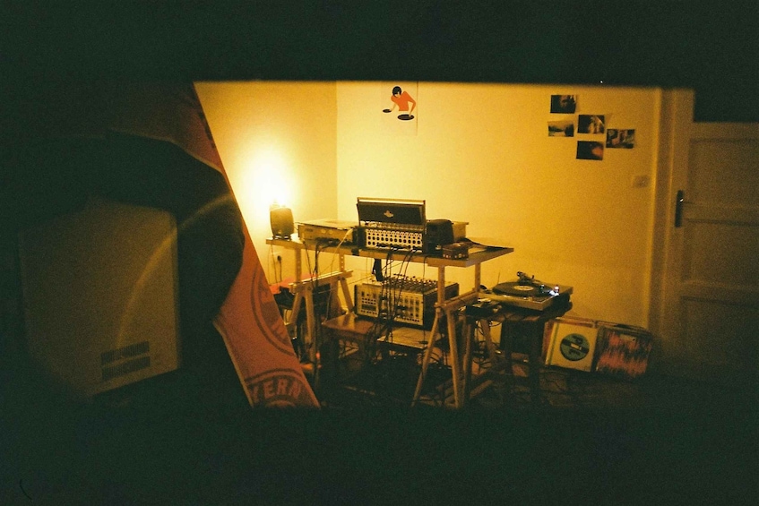 A dimly lit room with a computer setup, including a laptop and various electronic devices. 3