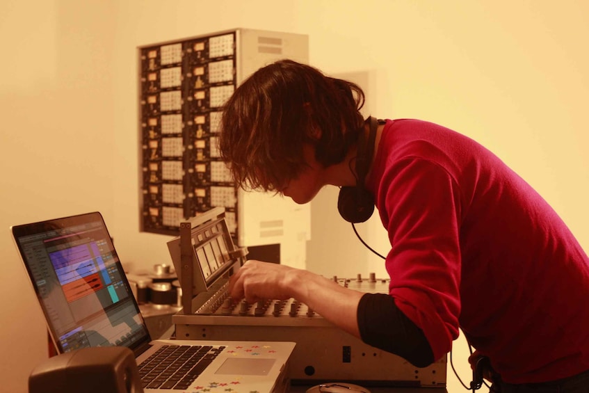 A person working at a desk with a laptop and a music mixing console. 4