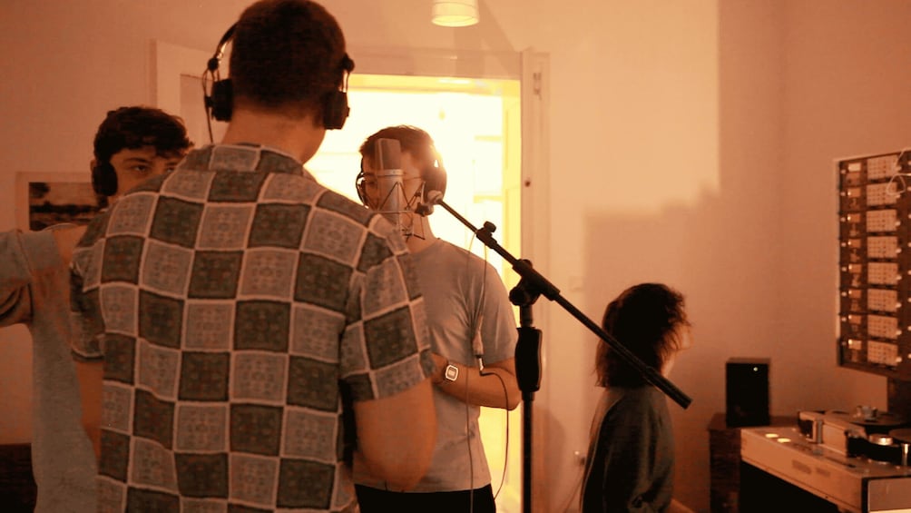 A recording studio with people singing into microphones. 2