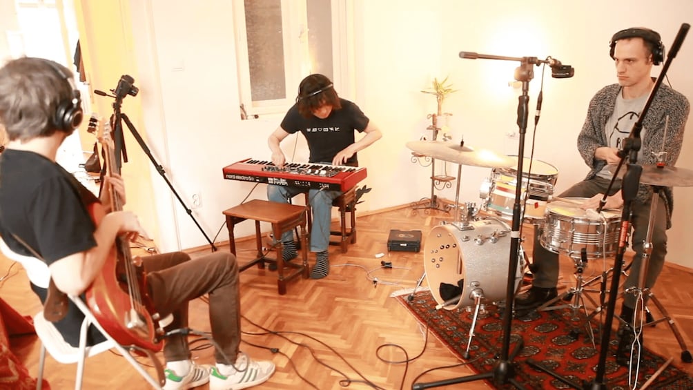 A band performing with a keyboard, drums, and a guitar. 1