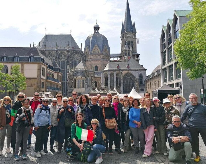 A group of people posing in front of a historic cathedral with a tall spire and a large dome. 3