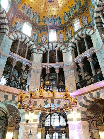A grand cathedral interior with ornate mosaics, marble columns, and a central golden altar. 5