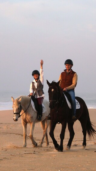 Two people riding horses on a beach. 2
