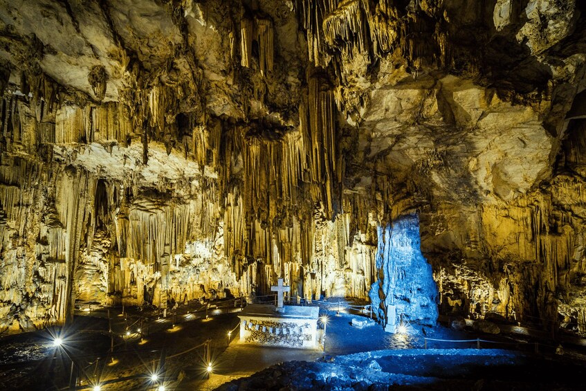 A cave with stalactites and stalagmites, illuminated by artificial lighting. 2