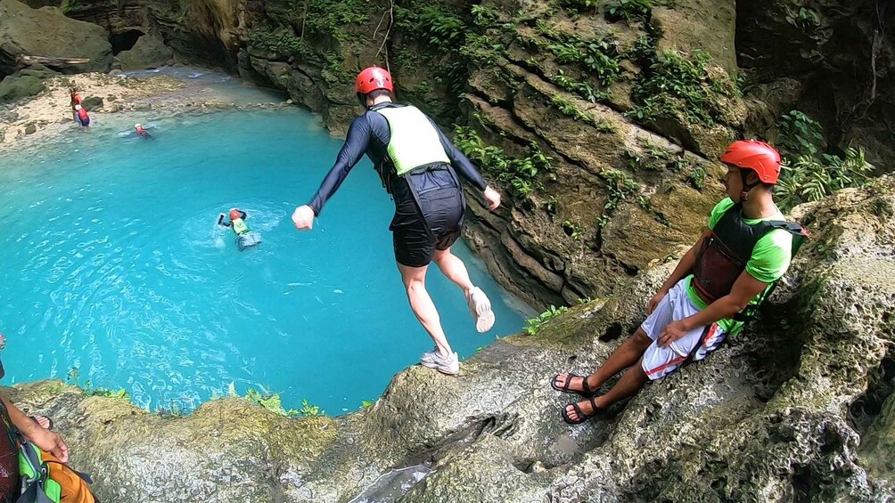 A person jumping into a clear blue pool from a rocky cliff. 5