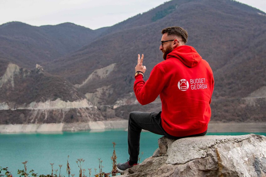 A person sitting on a rock by a lake with mountains in the background. 5