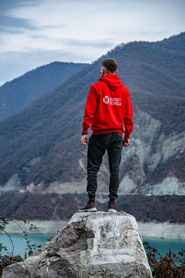 A person standing on a rock with a mountainous landscape in the background. 3