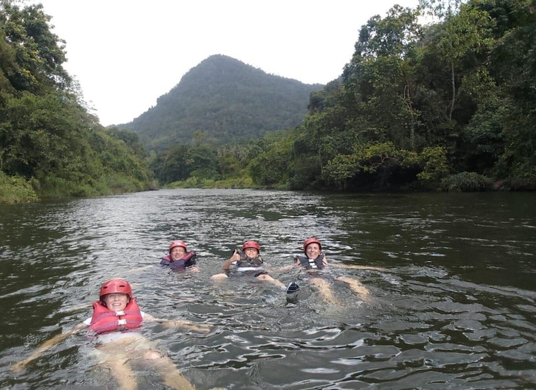 Four people kayaking on a river surrounded by dense forest and a mountain in the background. 2