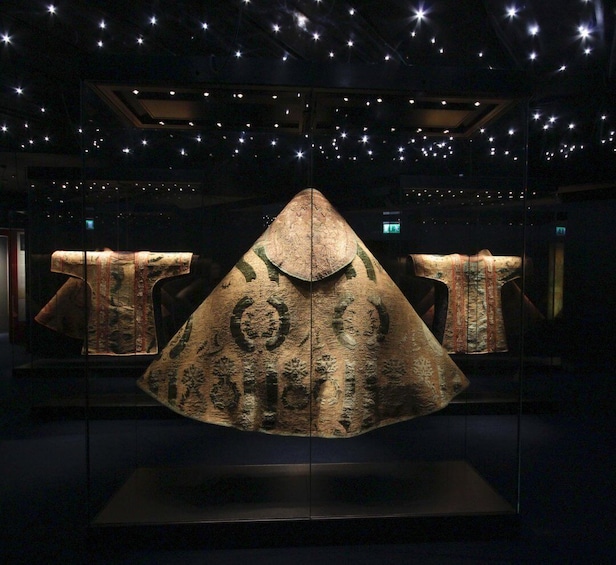 A museum display with a large, ornate, triangular artifact in the center, surrounded by smaller items. 1