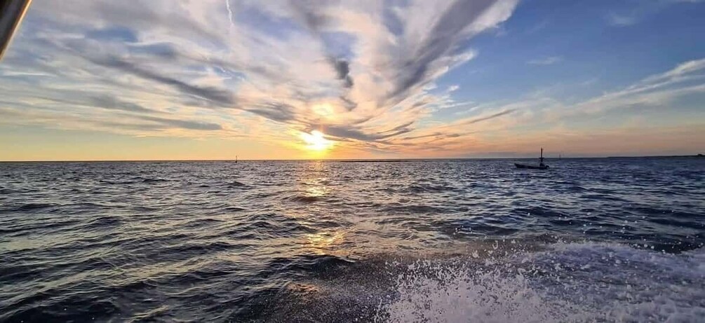 A sunset over the ocean with a boat in the distance. 5