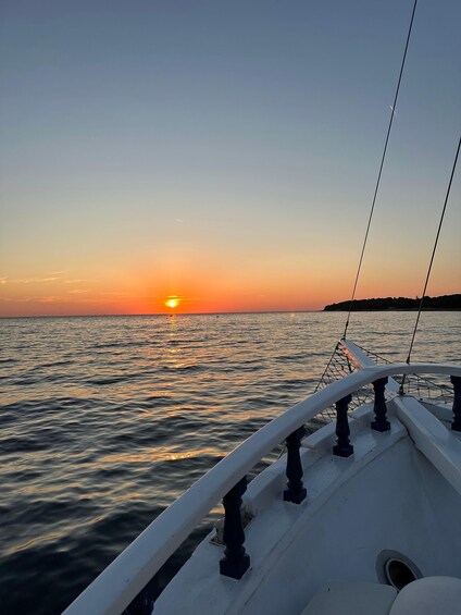 A sunset over the ocean with a boat's railing in the foreground. 4