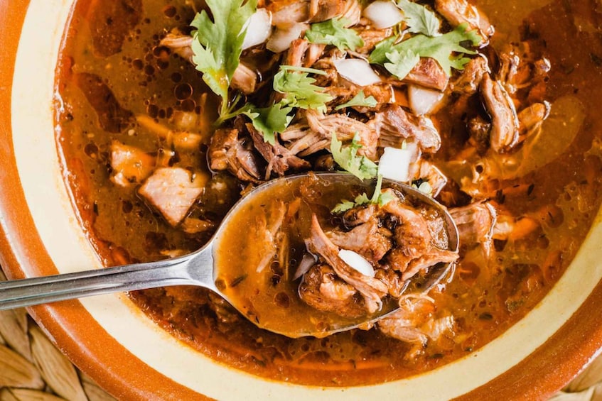 A bowl of stew with shredded meat and herbs. 4