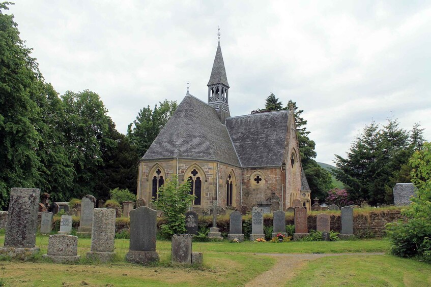 A church with a pointed steeple and a graveyard with headstones. 4