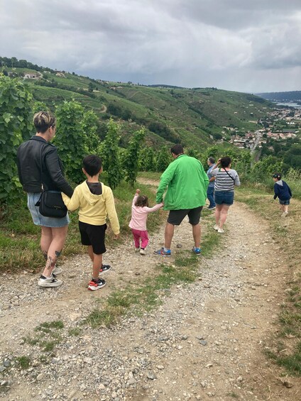 A group of people walking on a dirt path with a view of a valley and distant buildings. 5