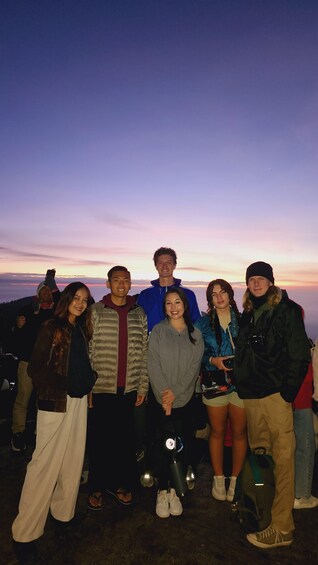 A group of people posing for a photo with a sunset in the background. 4