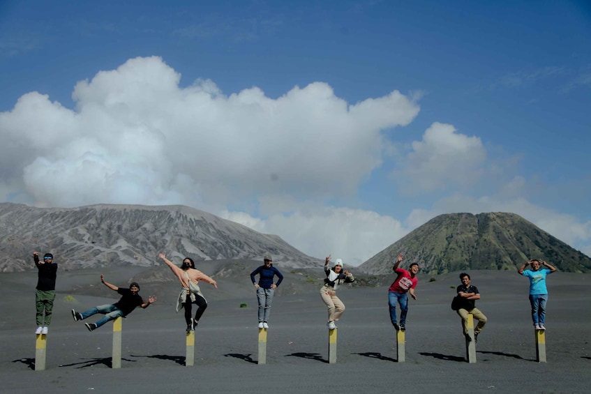 A group of people performing a balancing act on poles in a volcanic landscape. 5