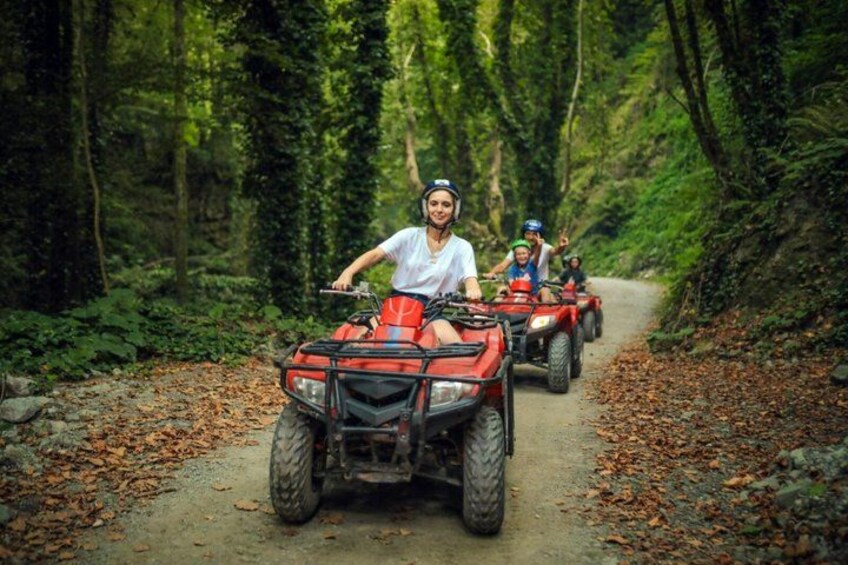 A group of people riding ATVs on a forest trail. 2