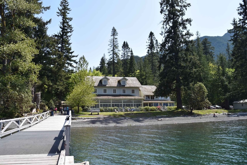 A lakeside lodge with a dock, surrounded by tall trees and mountains in the background. 4