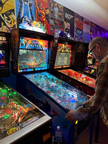 A person playing a pinball machine with a vibrant display and multiple screens. 4