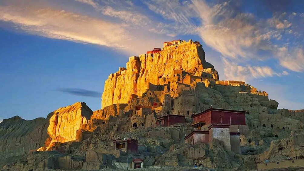 A rugged mountain with a large rock formation and several buildings at its base. 1