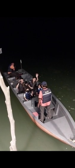 A boat with people wearing life jackets, a person in a pink shirt, and a person in a black vest with 'TAP' on it. 2