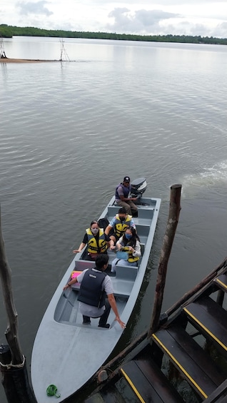 A rowboat with passengers wearing life jackets, docked at a pier. 4