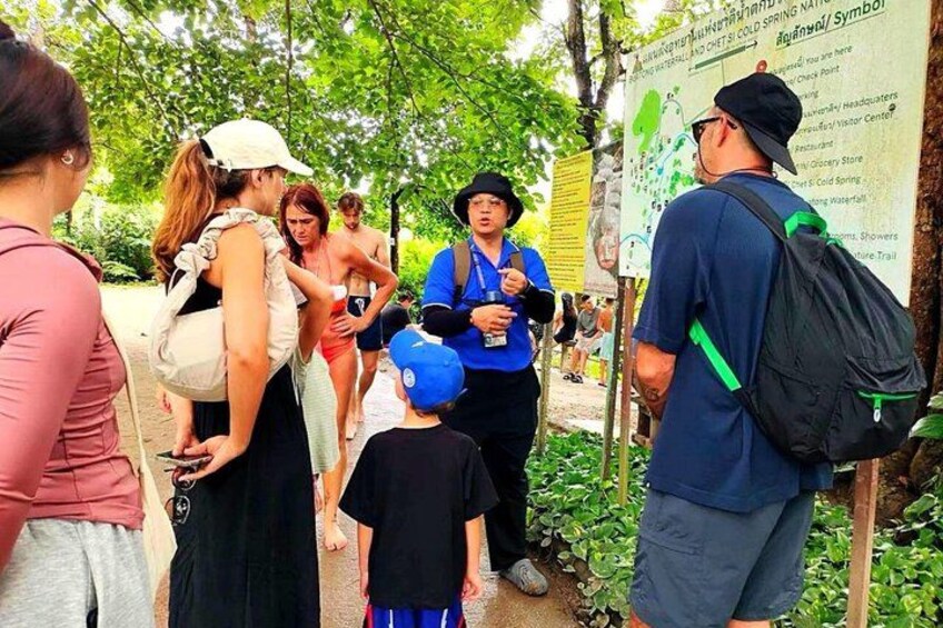A group of people standing near a signpost in a park. 5