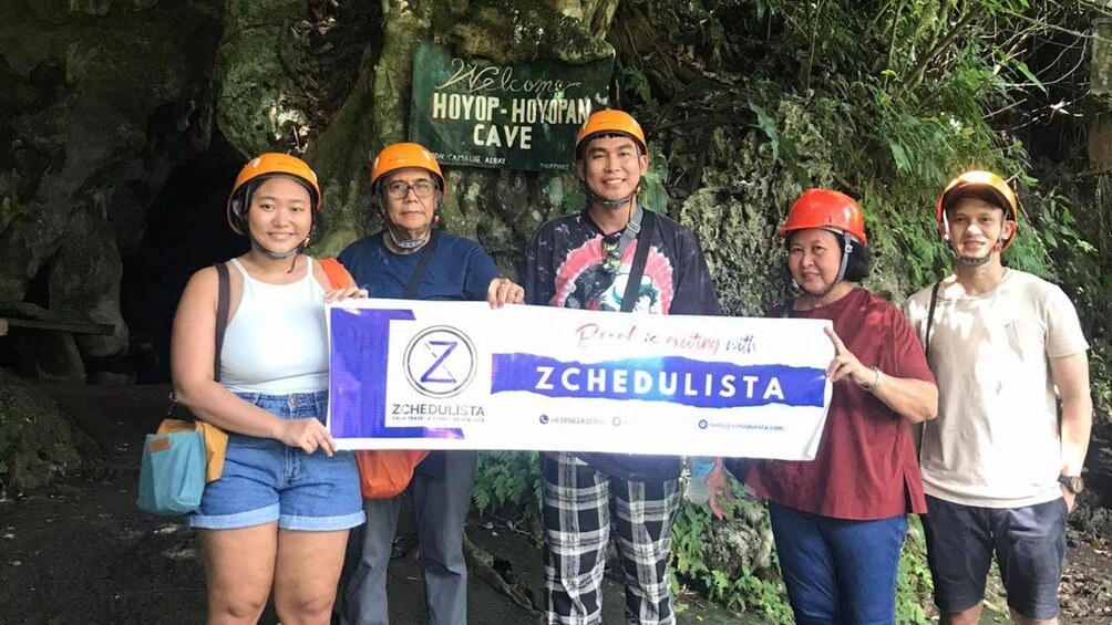 A group of people in a cave holding a Zchedulista banner. 3