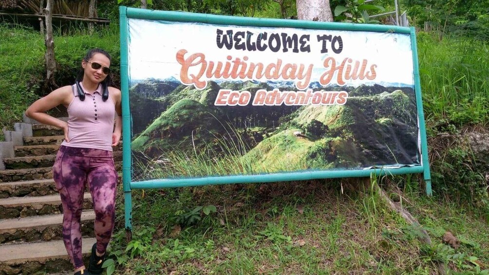 A person standing next to a sign that reads 'Welcome to Quitinday Hills Eco Adventures.' 2