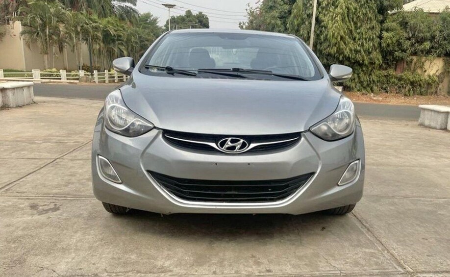 A silver Hyundai car parked on a concrete surface with palm trees and a fence in the background. 5