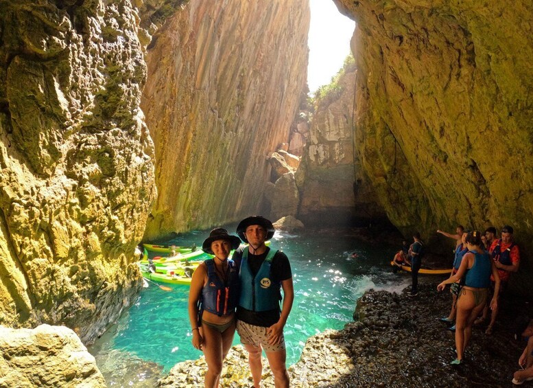 A group of people in a narrow canyon with a river, some standing and some in kayaks. 1