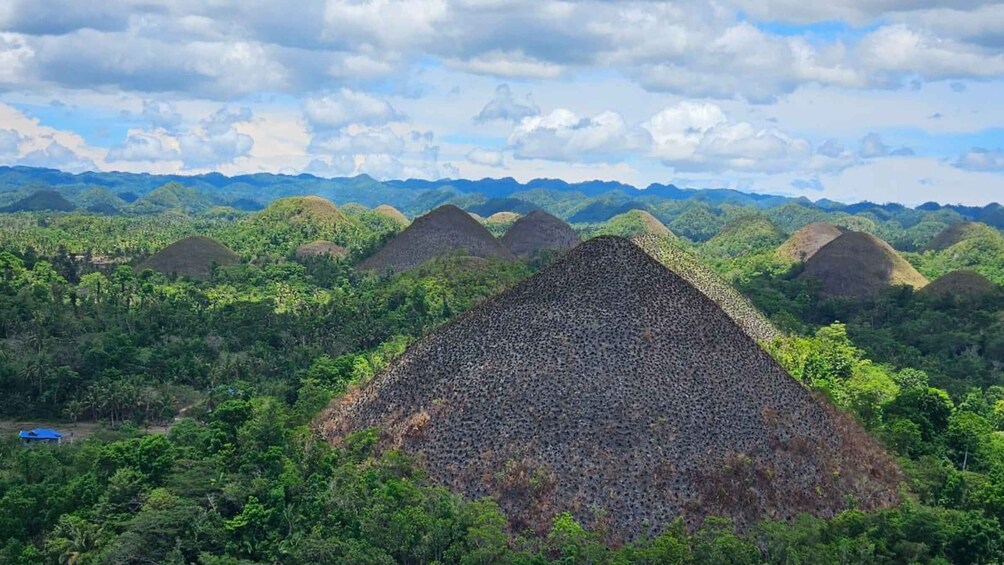 A landscape with a large pile of volcanic ash in the foreground and a range of mountains in the background. 1