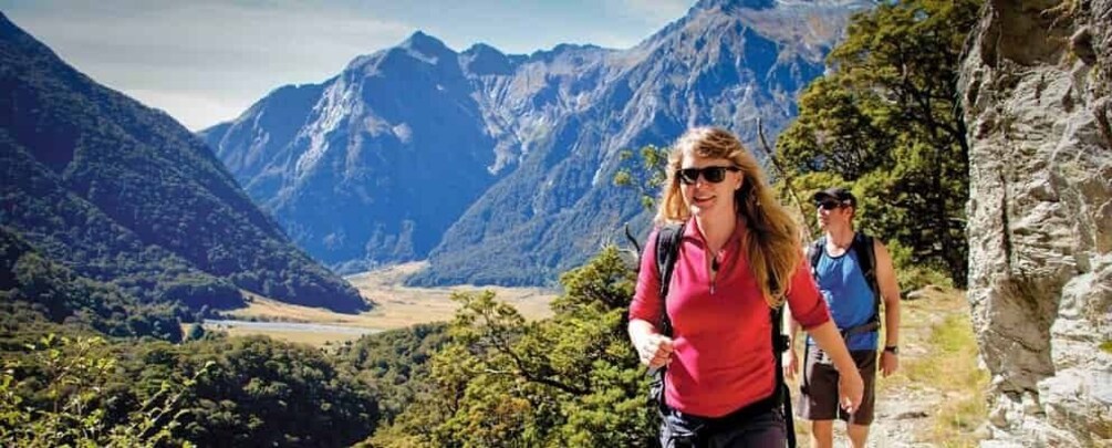 A hiker in a red shirt and a backpack walking on a trail with a mountainous landscape in the background. 5