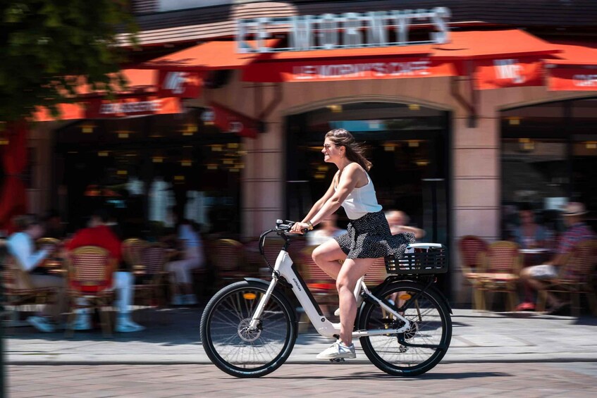 A person riding a white electric bicycle on a city street. 4