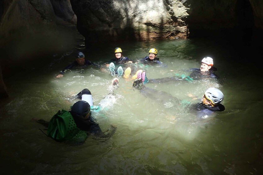 A group of people in a cave with water, wearing helmets and life jackets. 4