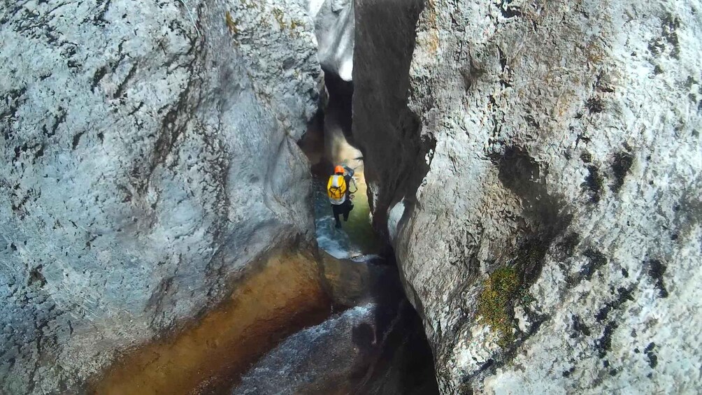 A narrow canyon with a person wearing a helmet and harness, possibly engaged in a water-based activity. 1
