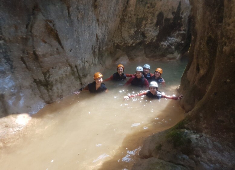 A group of people in a narrow water channel wearing helmets and life jackets. 3