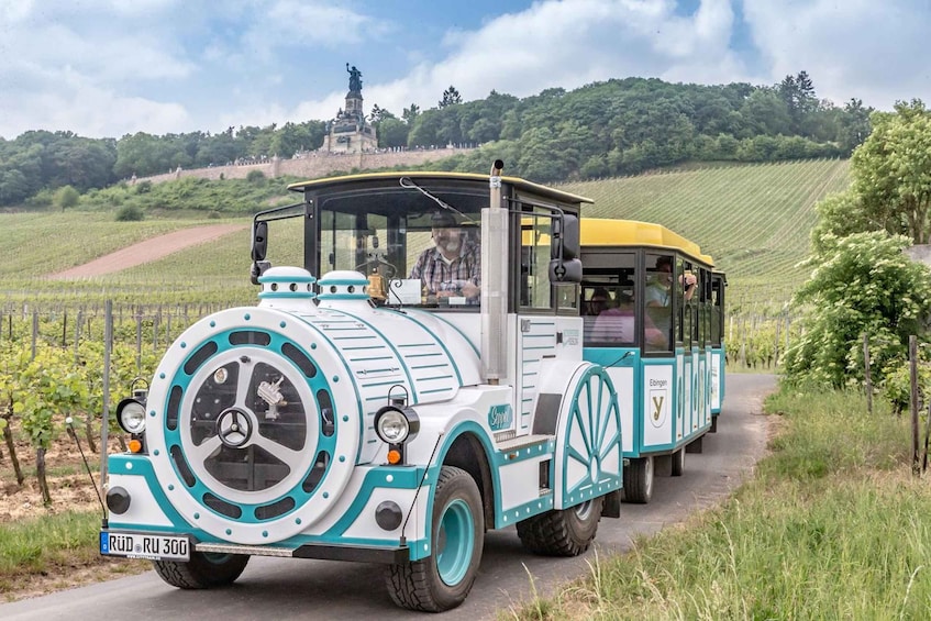 A vintage tram with a distinctive design, traveling through a vineyard. 1