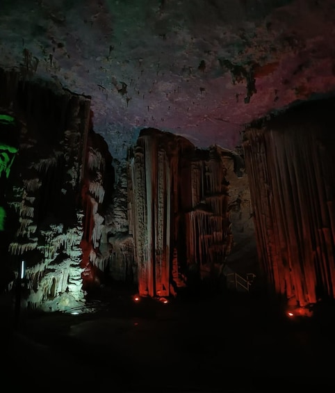 A cave with stalactites and stalagmites illuminated by red lighting. 5