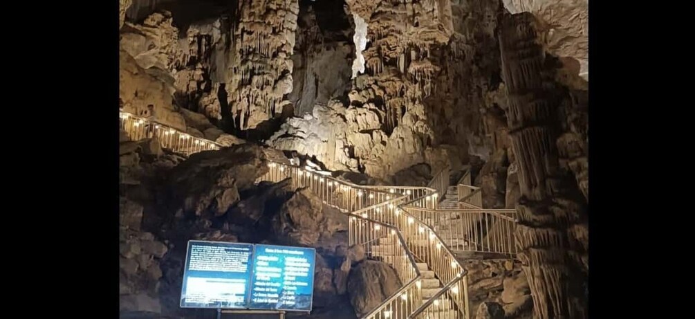 A cave with illuminated staircases and a signboard. 3