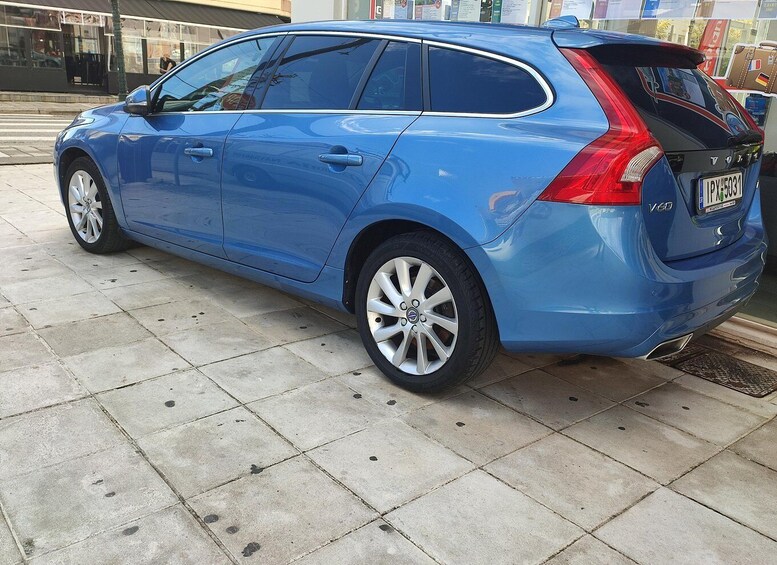 A blue station wagon parked on a tiled pavement. 4