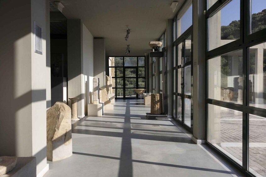 A corridor with large windows, stone sculptures, and a view of a building with trees. 5