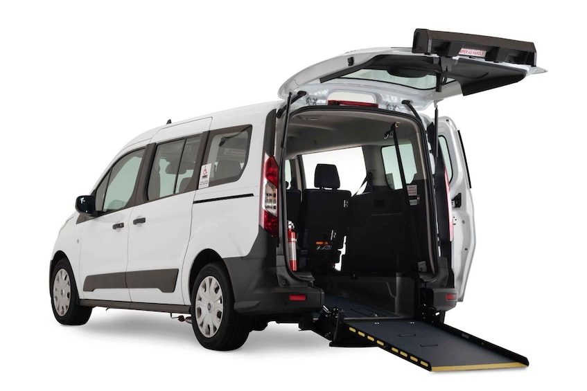 A white van with its rear door open and a ramp extended from the back. 5