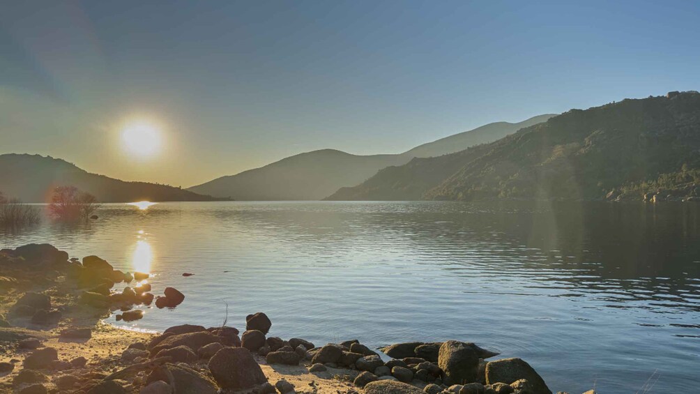 A calm lake with a mountain in the background and the sun reflecting on the water. 5