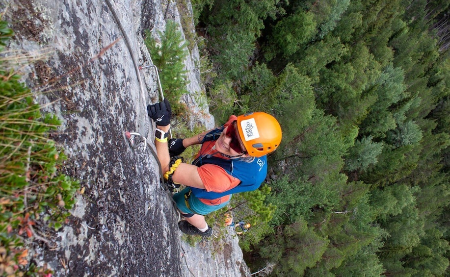 A person climbing a rocky cliff with a helmet and harness. 1