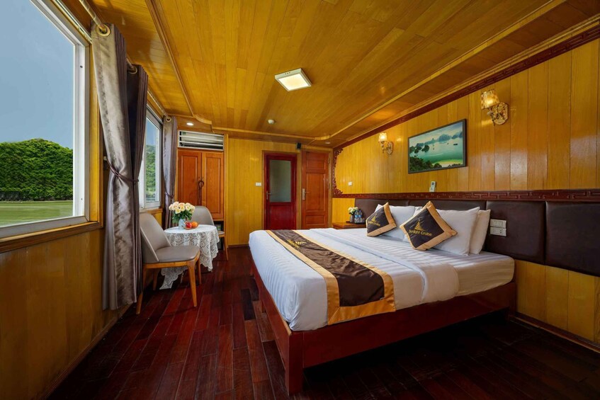 A wooden cabin with a bed, a table with a chair, and a window with curtains. 2