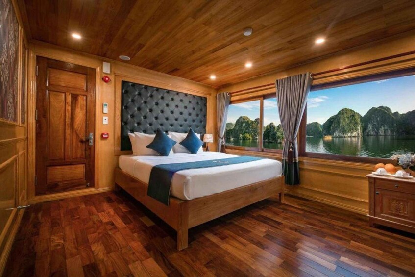 A wooden cabin bedroom with a bed, a window with a view of a lake and mountains, and a wooden floor. 5