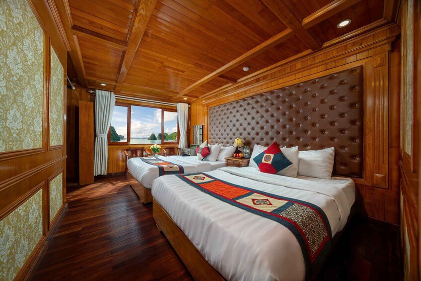 A wooden-paneled bedroom with a large tufted headboard, two beds, and a view of the sea. 3