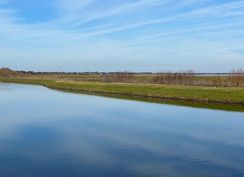 A calm river with grassy banks and a clear sky. 4